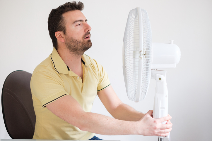 Man refreshing in front of air electric fan