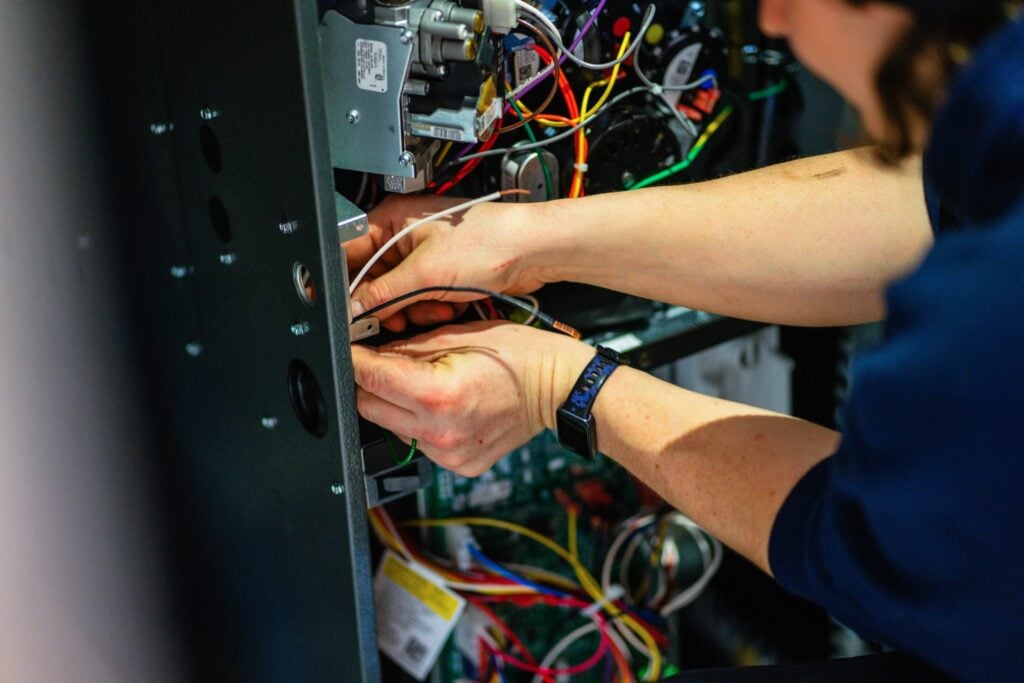 Technician performing professional furnace repair and wiring maintenance in Durham Region.