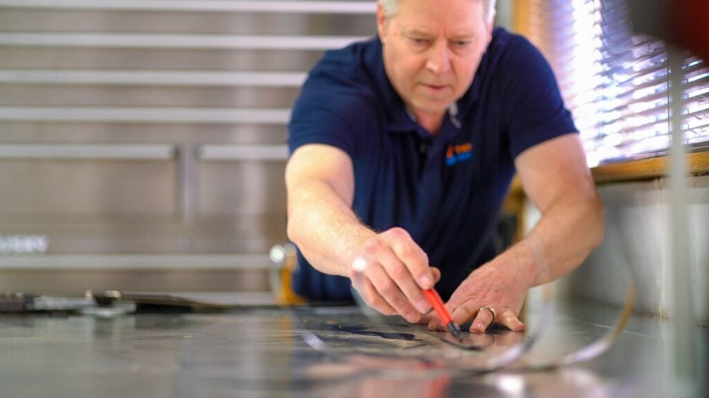 Twintech technician measuring metal sheet for custom HVAC ductwork installation in Durham Region.